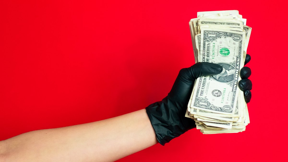 Ręka w czarnej rękawiczce trzymająca pieniądze