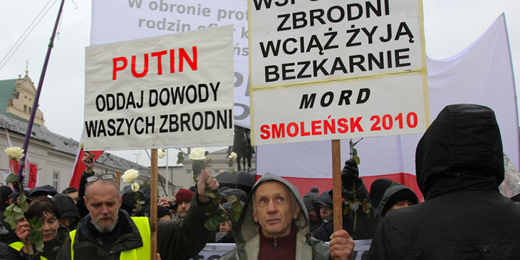 Uczestnik Miesięcznicy Smoleńskiej z transparentami, których treść sugeruje, że katastrofa była skutkiem zamierzonego działania.