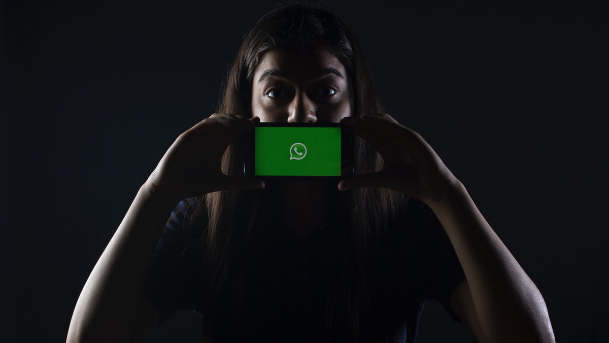 Kobieta trzymająca smartfon z logiem WhatsApp