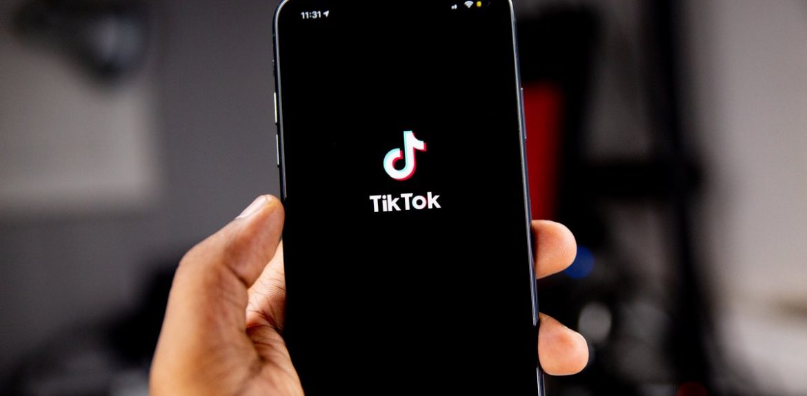 Mężczyzna trzymający smartfon z logiem TikToka